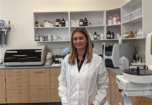 Woman in lab coat stands in laboratory. 