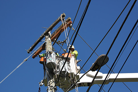 Line crews replacing power pole crossarms