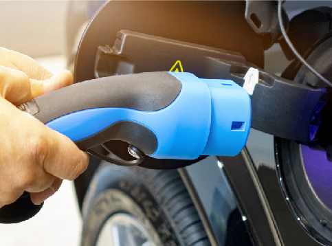 A person's hand holding an EV charger and about to plug-in