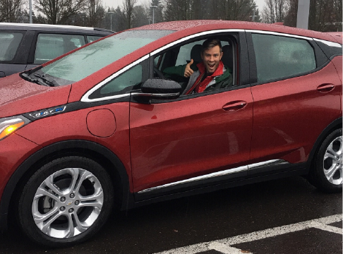 EWEB customer giving a thumbs up in his red Chevy Bolt