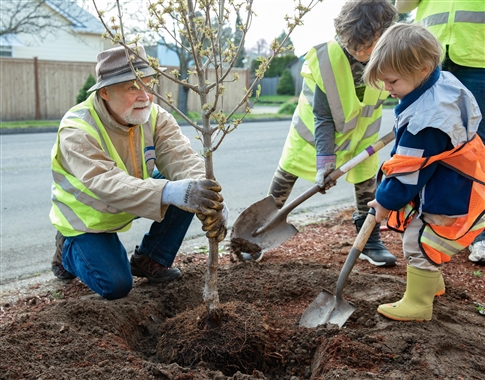 Friends of Trees volunteer helps a young boy plant a tree