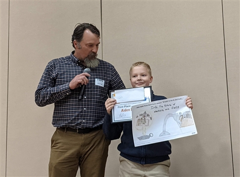 EWEB commissioner Matt McRae with 1st place poster contest winner Aiden Muller.