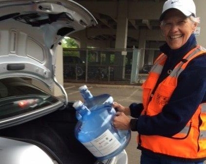 smiling woman loading emergency water containers into her car