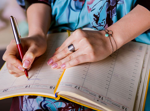 Woman writing in calendar while doing her budget