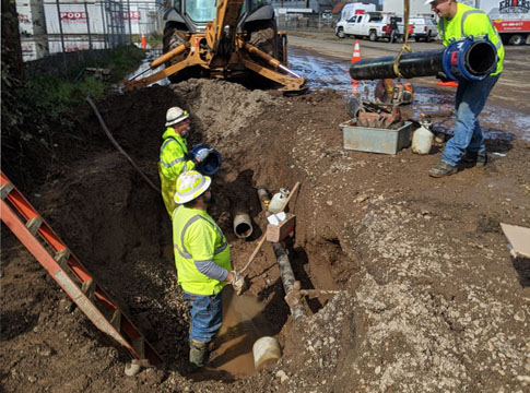 Crews repair a broken water main while observing social distancing rules