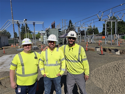three men stand in front of substation project