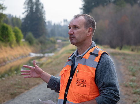 EWEB engineer gesturing toward Leaburg canal as he describes the project