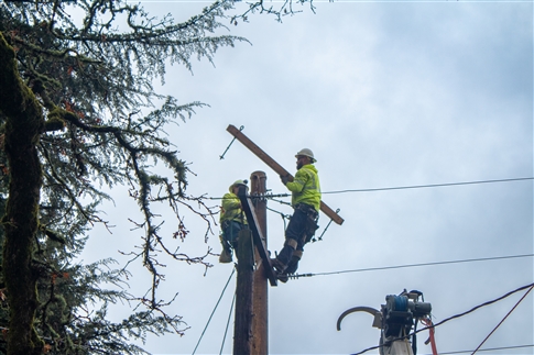 lineman moves a cross arm on an electric pole