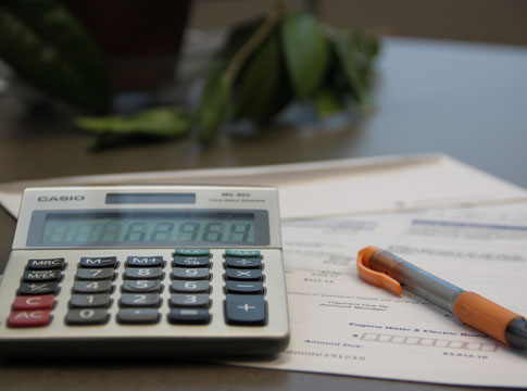 Picture of a utility bill, calculator and pencil on a desk