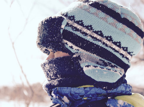 Child bundled up for cold weather in a hat and scarves.