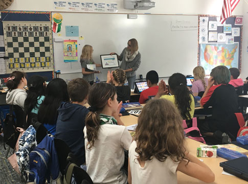 Sonya Carlson presenting girl with award in front of classmates