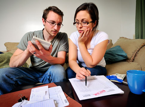 Young couple looking at calculator while paying bills