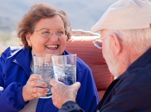 smiling man and woman clinking water glasses