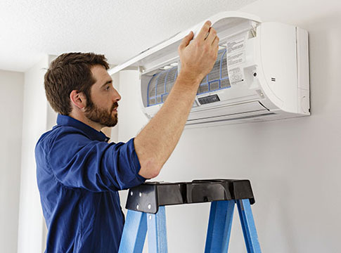 Man checking filter on ducltess heat pump