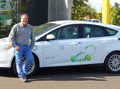 EWEB Fleet Supervisor leaning on electric car