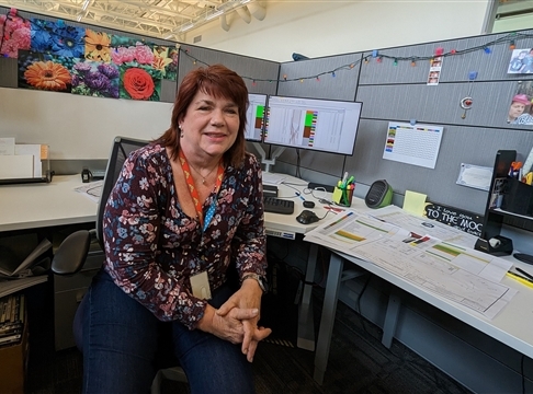 Woman sits at desk smiling.