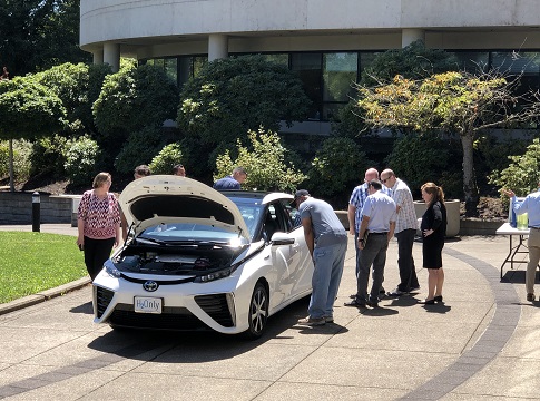 Picture of Toyota Mirai parked at the EWEB riverfront plaza with several people checking out the zero-emission hydrogen fuel cell vehicle