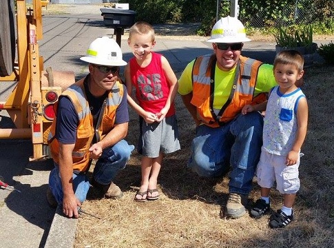 Picture of 2 EWEB line techs posing with kids