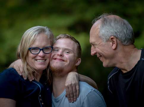Mom hugging son with dad smiling
