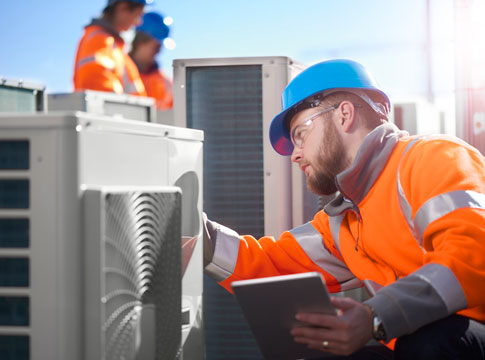 Technician in hardhat inspecting an HVAC system