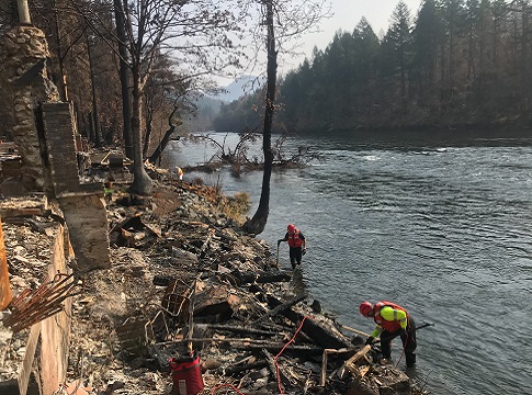 Workers removing burned hazardous debris away from the riverbank