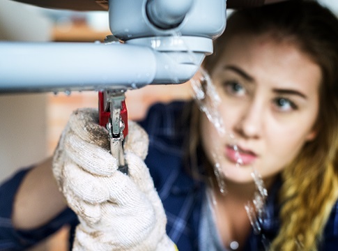 Picture of a woman fixing a leaky pipe under the sink