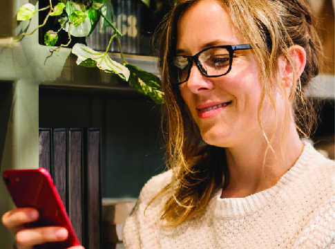 A woman with black glasses holding a red cell phone