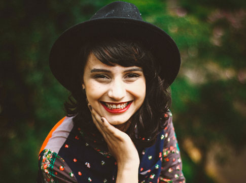 Young woman in a hat smiling at the camera.