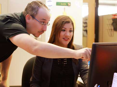 A woman and man working together on a computer.