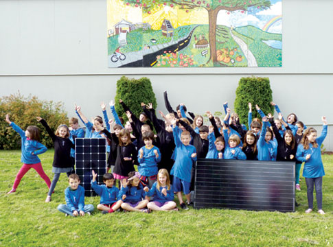School children gathered around solar panels in celebration of their elementary school winning a Greenpower Grant.