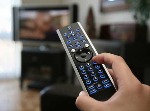 Hand holding a remove pointed at a television.