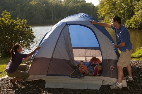 Picture of family setting up a tent by a lake