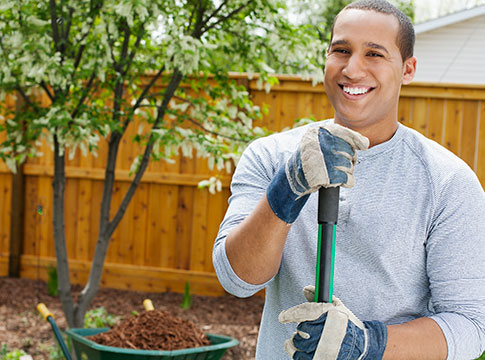 Young adult man holding shovel in front of tree