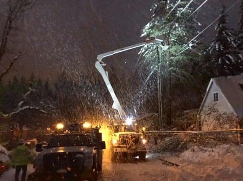 Crews working at night in a snow storm to restore power